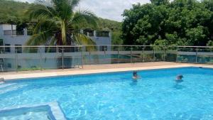 two people in a swimming pool with a palm tree at Casa Nueva en Condominio in Girardot