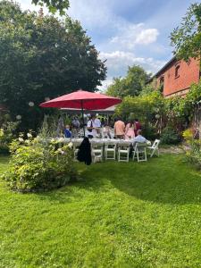 a group of people sitting at a table under a red umbrella at Sommerhof im Havelland in Nennhausen +29 photos