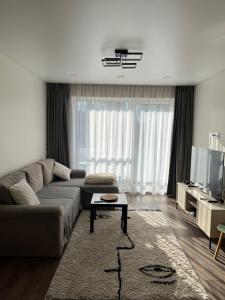 a living room with a couch and a table at Modern apartment with Private parking - 10 min to airport, 15 min Center in Vilnius