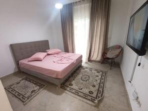 a bedroom with a pink bed and a television at Salem in Sidi Daoud