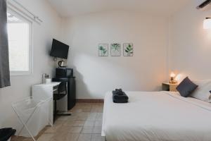 a white bedroom with two beds and a desk at Kavana Kata Residence in Phuket