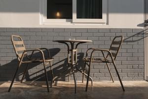 two chairs and a table in front of a brick wall at Kavana Kata Residence in Phuket