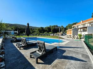 a swimming pool with two chairs and an umbrella at Villa Playa Covelo in Pontevedra