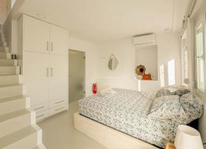 a white bedroom with a bed and a staircase at Casa Calliope in Playiá