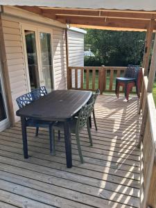 a wooden deck with a picnic table and chairs at Mobil home 590 in Pont-Aven