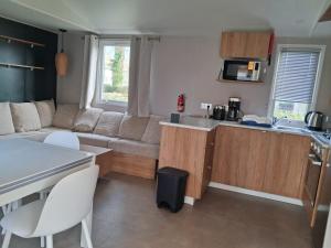 a kitchen and living room with a couch and a table at Mobil home 590 in Pont-Aven +5 photos