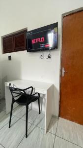 a desk with a chair and a television on a wall at Pousada Só Alegria in Fortaleza