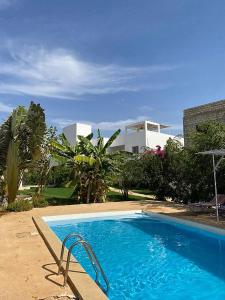 a large blue swimming pool in front of a house at Villa Saraba in Somone