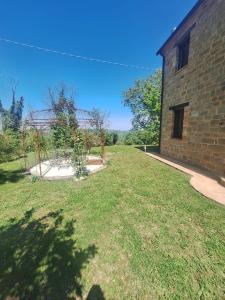 a grassy yard with a building and a garden at casa Bel Posto in San Ginesio
