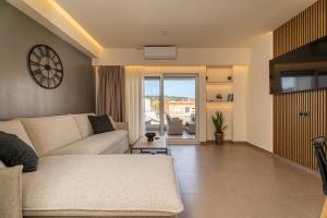 a living room with a couch and a clock on the wall at The Mall Luxury Suites in Nikiti
