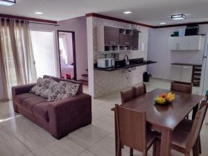 a living room and kitchen with a couch and a table at Refúgio Guarajuba, 50m da Praia, Piscina, Recarga EV, área gourmet, churrasqueira in Camaçari
