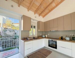 a kitchen with white cabinets and a large window at Casa Calliope in Playiá +23 photos