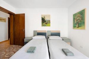 two beds in a room with a door and paintings at Ca' Due Cuori in Torri del Benaco