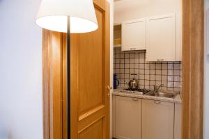 a kitchen with white cabinets and a light and a door at Residence Casa Gardola, GTSGroup in Tignale