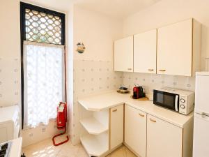 a small kitchen with a microwave and a window at Appartamento Eunoia I TerraceParking&AC in Lignano Sabbiadoro +2 photos
