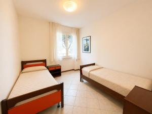 a bedroom with two beds and a window at Appartamento Eunoia I TerraceParking&AC in Lignano Sabbiadoro