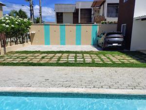 a house with a swimming pool in front of a house at Refúgio Guarajuba, 50m da Praia, Piscina, Recarga EV, área gourmet, churrasqueira in Camaçari