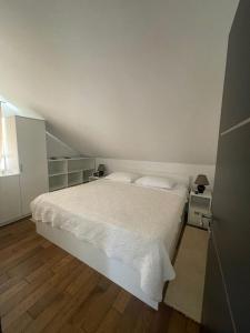 a bedroom with a white bed and wooden floors at My place Čiovo holiday house in Žedno +22 photos