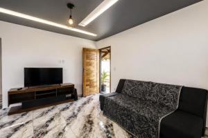 a living room with a couch and a flat screen tv at Morada Iluminada Aconchego com Ar condicionado e Lareira in Miguel Pereira