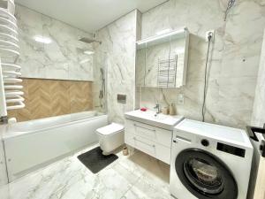 a white bathroom with a washing machine in it at Voloshyna Central Loft in Ivano-Frankivsk