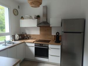 a kitchen with white cabinets and a stainless steel refrigerator at Maison des bois in Neufchâtel-Hardelot