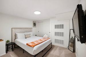 a bedroom with a large white bed and a television at Seatac Lake Cottage A2 in SeaTac