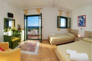 a hotel room with two beds and a balcony at Felix Residence & Lucia Simona Villas in Mousata