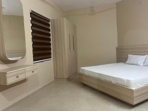 a bedroom with a bed and a dresser and a mirror at S S Apartment in Kannur