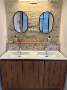 a bathroom with two sinks and two mirrors at Chambre d'hôtes Camélia in Saint-Lyphard