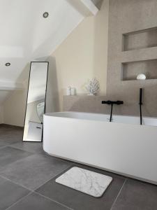 a bathroom with a white tub and a mirror at La Parenthèse des Charmes in Andenne