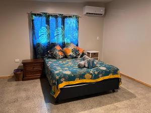 ein Schlafzimmer mit einem Bett mit einem blauen Fenster in der Unterkunft Mareva Kore in Avarua