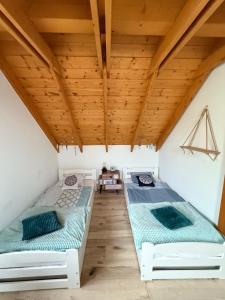 two beds in a room with wooden ceilings at Nadbużańska Ostoja in Kamieńczyk