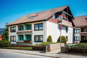 a white house with a brown roof on a street at MiraBlau Braunlage in Braunlage +8 photos