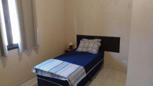 a small bedroom with a bed with a pillow and a window at Sobrado entrada de Paraty in Paraty