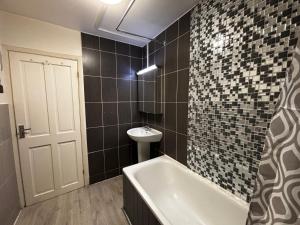 a bathroom with a tub and a sink and a toilet at Emerald Room - shared bathroom in Ponders End