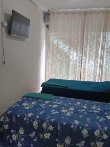 a bedroom with a bed with a blue comforter and a window at Refugio das Laranjeiras Hospedagem in Piraí
