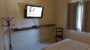 a room with a television on a wall with a bed at Sobrado entrada de Paraty in Paraty