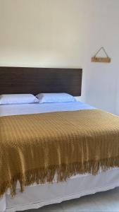 a bedroom with a large bed with a gold bedspread at Cantinho da Beth in Caravelas +2 photos