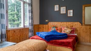 a bedroom with two beds with red and blue sheets at Casa Nova in Manāli