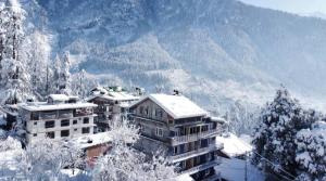 a building covered in snow with a mountain in the background at Casa Nova in Manāli