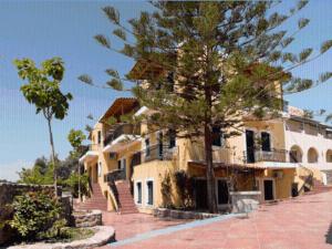 a large building with a tree in front of it at Venetia Studios in Perdika