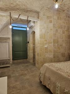 a bedroom with a green door in a stone wall at Stanza29 in Martina Franca