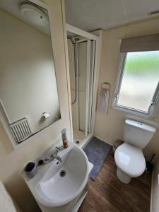 a bathroom with a sink and a toilet and a mirror at Manderley Caravan in Newquay Bay Resort