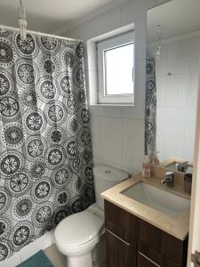 a bathroom with a toilet and a sink and a shower curtain at LUGAnO 301 in Temuco +9 photos