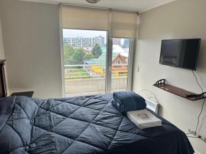 a bedroom with a bed with a tv and a window at LUGAnO 301 in Temuco