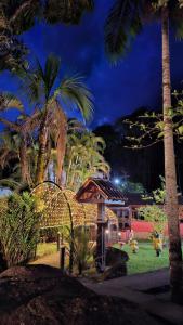a house with palm trees in a park at night at Pousada Luar de Penedo in Penedo