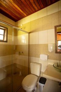 a bathroom with a toilet and a glass shower at Pousada Recanto do Pico in Santo Antônio do Pinhal