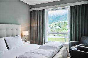 a bedroom with a bed and a window and a chair at Skjolden Hotel in Skjolden