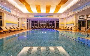 a large swimming pool in a hotel with chairs at Haus Barnheide - Wohnung Sandburg in Bansin