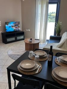 a living room with a table and chairs and a television at Kaloula's home in Keramoto